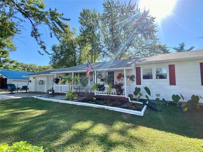 Ranch-style home with a front yard, a porch, and a garage | Image 1