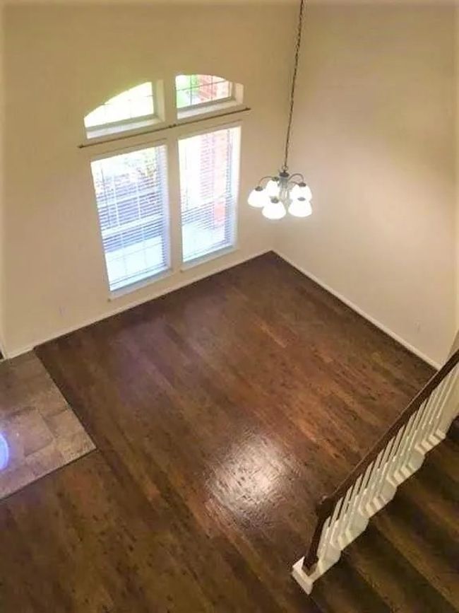 Unfurnished dining area with dark wood-style flooring, a chandelier, stairs, and baseboards | Image 6