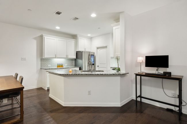 Kitchen featuring smart refrigerator, visible vents, backsplash, light stone counters, and white cabinets | Image 8