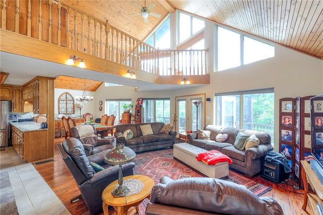 Living area featuring high vaulted ceiling, plenty of natural light, a chandelier, wooden ceiling, and light tile patterned floors | Image 7