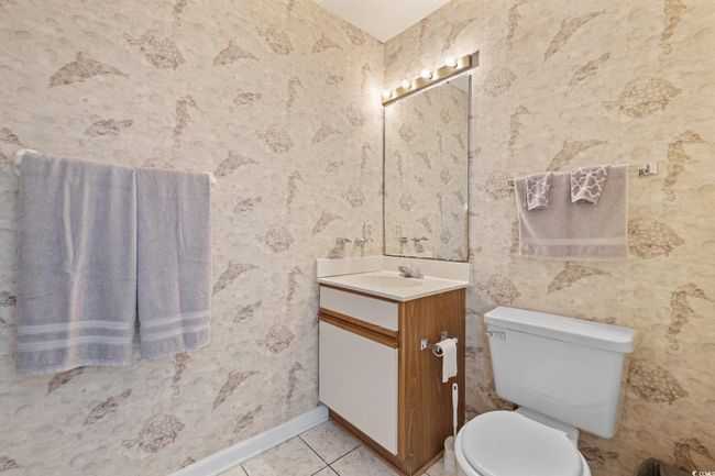 Half bathroom with vanity, wallpapered walls, toilet, baseboards, and tile patterned flooring | Image 15