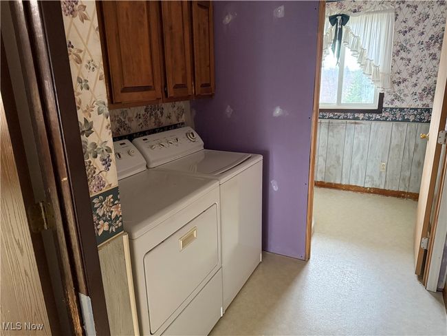 Laundry room with baseboards, washer and clothes dryer, cabinet space, and wallpapered walls | Image 33