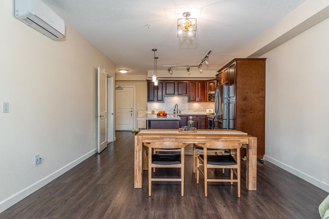 Dining area with a wall mounted air conditioner, dark wood finished floors, and baseboards | Image 12