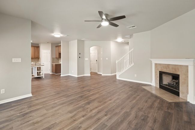Unfurnished living room featuring arched walkways, a ceiling fan, dark wood-style floors, and stairs | Image 9
