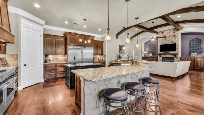 Kitchen with a large island, high quality appliances, ceiling fan, a stone fireplace, and open floor plan | Image 15