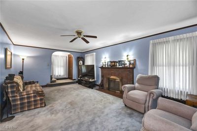 Carpeted living room featuring a fireplace, ornamental molding, and ceiling fan | Image 2