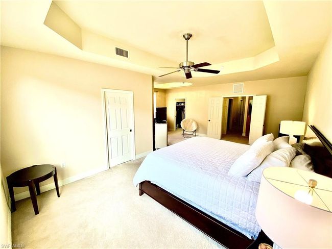 Bedroom with light carpet, baseboards, visible vents, ceiling fan, and a raised ceiling | Image 11