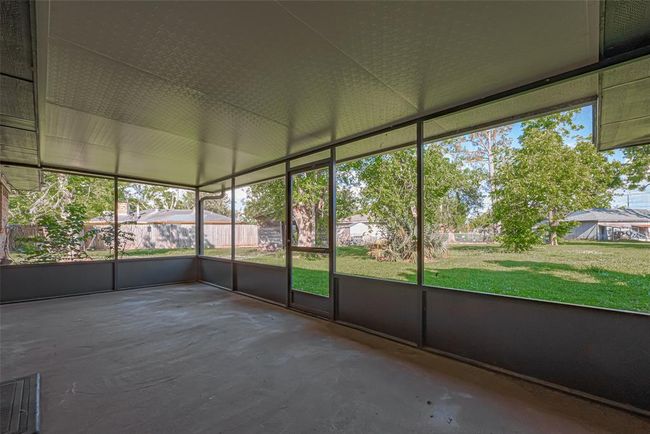Leading out of living area, covered back patio offers plenty of space for outdoor activities and relaxation, with a view of the backyard through screened panels. Enjoy the beauty of your backyard rain or shine! | Image 25