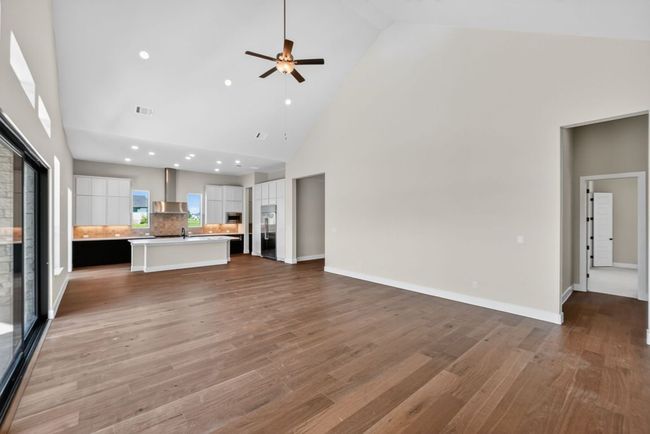 Unfurnished living room featuring high vaulted ceiling, light wood-type flooring, ceiling fan, and recessed lighting | Image 6