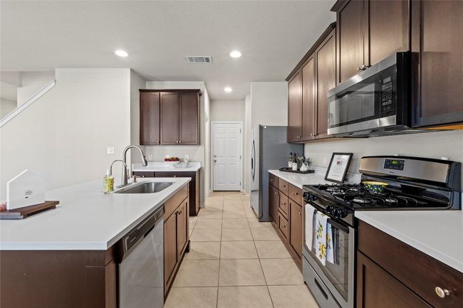 Kitchen featuring light countertops, visible vents, light tile patterned floors, a sink, and appliances with stainless steel finishes | Image 8
