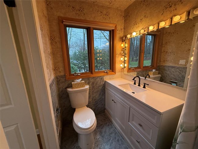 Bathroom featuring tile walls, toilet, vanity, and wainscoting | Image 12