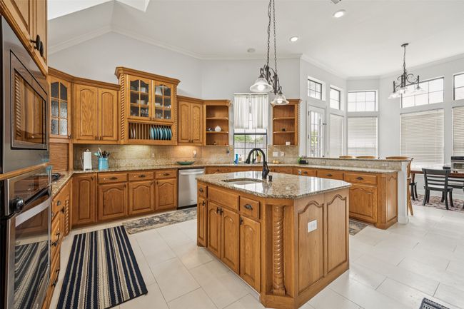 Kitchen with stainless steel appliances, open shelves, brown cabinets, plenty of natural light, and ornamental molding | Image 6