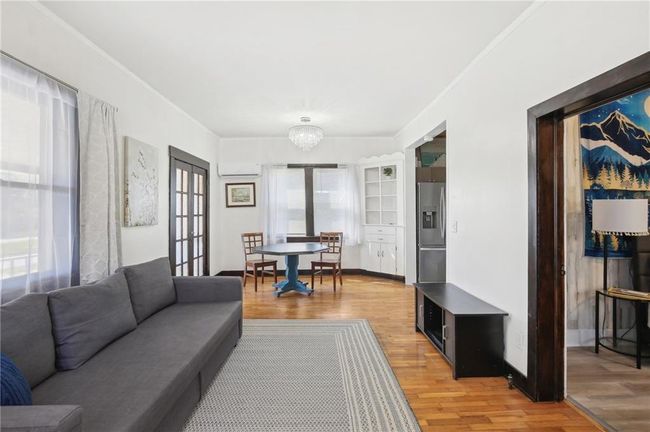Living room featuring a wall mounted air conditioner, an inviting chandelier, and wood finished floors | Image 4