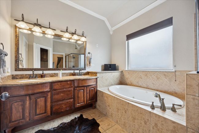 Bathroom with crown molding, a shower stall, a whirlpool tub, double vanity, and vaulted ceiling | Image 15