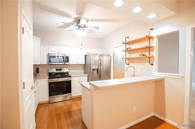 Kitchen featuring white cabinets, a peninsula, appliances with stainless steel finishes, and light wood-style floors | Image 6