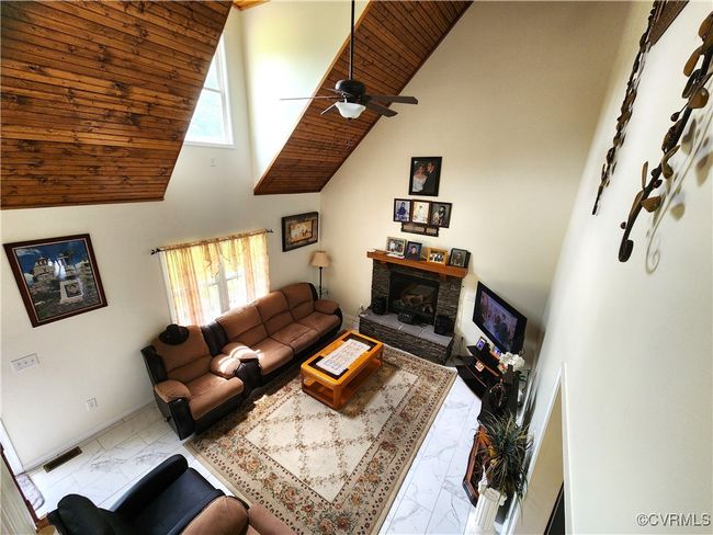 Living area featuring marble finish floors, wood ceiling, high vaulted ceiling, plenty of natural light, and a fireplace | Image 7
