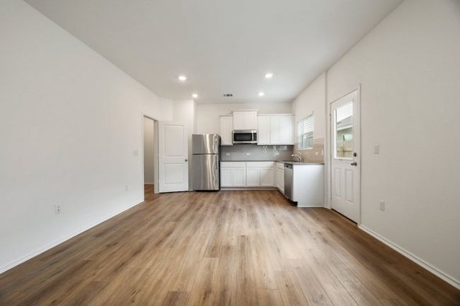 Kitchen featuring appliances with stainless steel finishes, wood finished floors, white cabinets, recessed lighting, and tasteful backsplash | Image 9