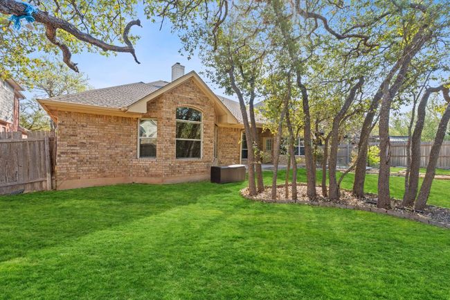 Rear view of property featuring a yard, fence, brick siding, a chimney, and a shingled roof | Image 36