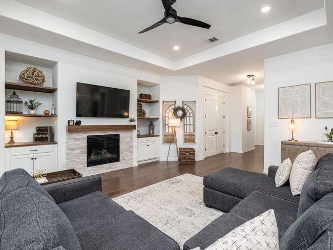 Living area featuring built in features, ceiling fan, dark wood finished floors, recessed lighting, and a tile fireplace | Image 4