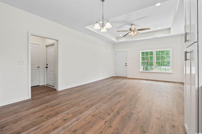 Unfurnished room featuring a tray ceiling, wood-type flooring, a chandelier, ceiling fan, and recessed lighting | Image 6