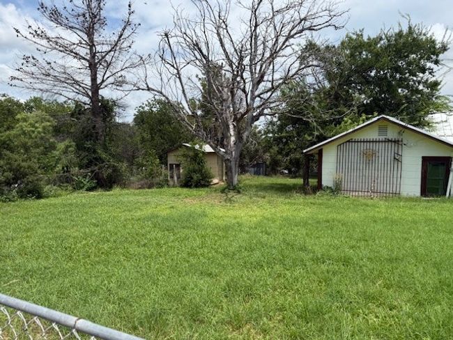 View of grassy yard featuring an outdoor structure and a detached garage | Image 16