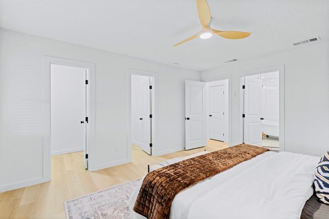 Bedroom featuring light wood finished floors, a walk in closet, ensuite bath, and ceiling fan | Image 16