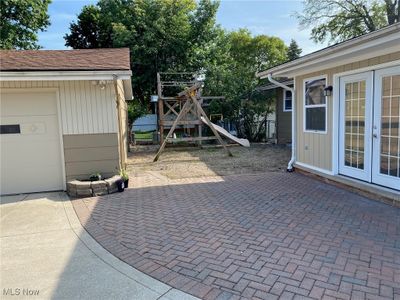 View of patio with a garage, a playground, and french doors | Image 2