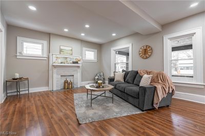 Living room with dark hardwood / wood-style flooring, a wealth of natural light, and a brick fireplace | Image 3