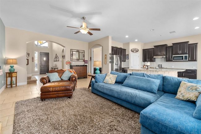 Living room with light tile patterned flooring, baseboards, ceiling fan, recessed lighting, and arched walkways | Image 7