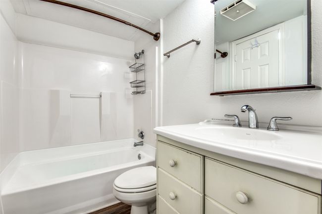 Full bathroom featuring wood-type flooring, toilet, shower / bathtub combination, and vanity with extensive cabinet space | Image 9