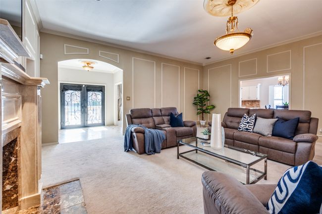 Carpeted living room with ornamental molding, arched walkways, french doors, and a decorative wall | Image 9