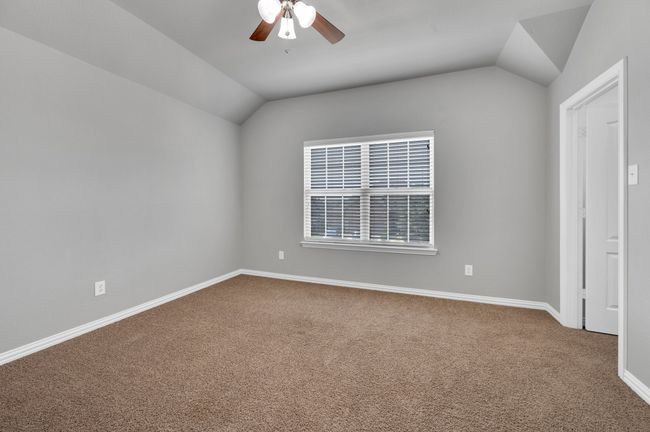 Secondary bedroom featuring vaulted ceiling, carpet flooring, and ceiling fan. | Image 24