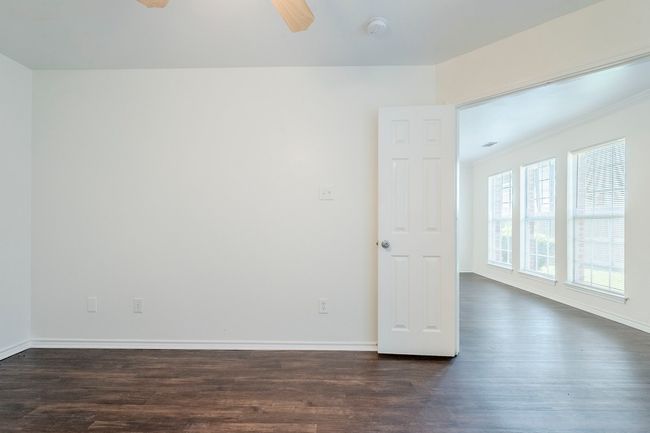 Spare room with dark wood-style floors, ceiling fan, a smoke detector, and crown molding | Image 16