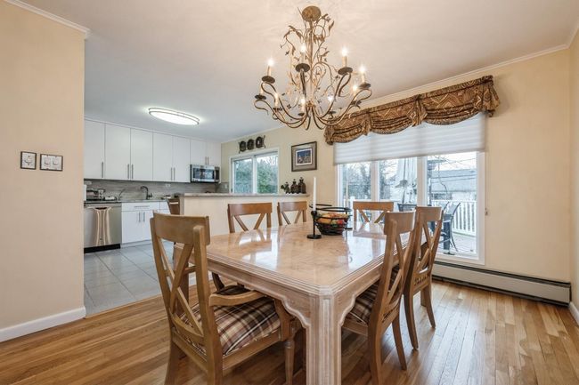 Dining space with a baseboard radiator, an inviting chandelier, crown molding, and light wood finished floors | Image 10
