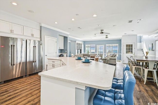 Kitchen with high end refrigerator, a center island, white cabinets, open floor plan, and recessed lighting | Image 6