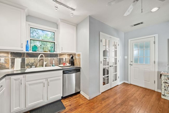Kitchen featuring dishwasher, french doors, light wood-type flooring, backsplash, and rail lighting | Image 6
