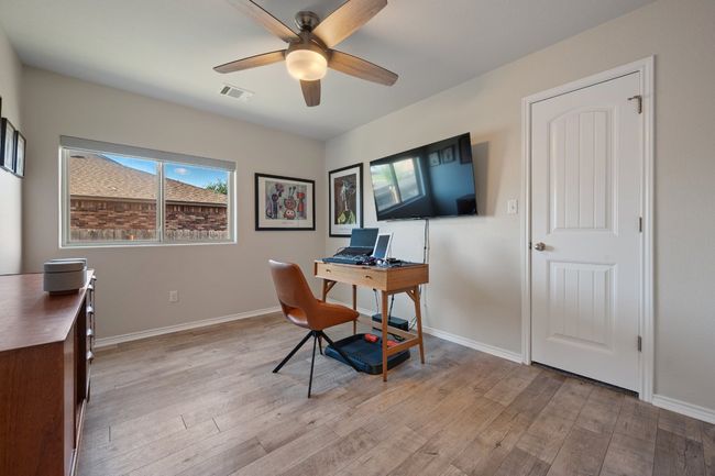 Home office featuring light wood-type flooring, baseboards, a ceiling fan, and visible vents | Image 15