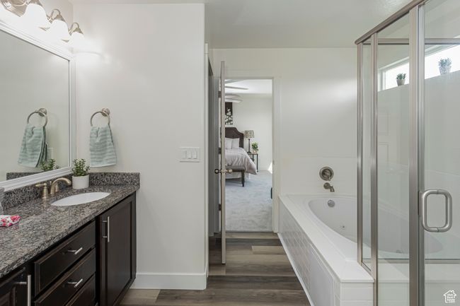 Ensuite bathroom featuring vanity, a whirlpool tub, a stall shower, baseboards, and wood finished floors | Image 18