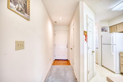 Hall with light colored carpet and a textured ceiling | Image 3