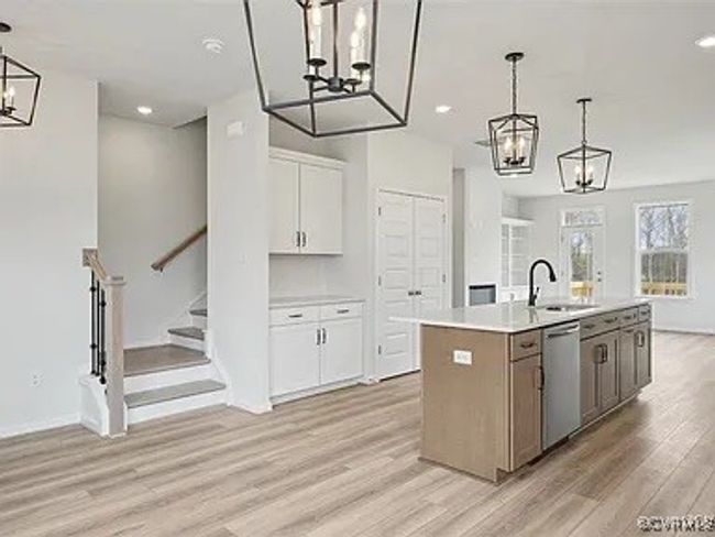 Kitchen with a chandelier, dishwasher, light wood-style flooring, white cabinets, and a kitchen island with sink | Image 14