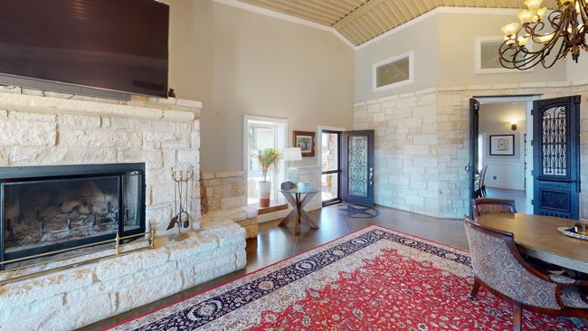 Entryway featuring crown molding, a fireplace, an inviting chandelier, high vaulted ceiling, and tile patterned flooring | Image 7