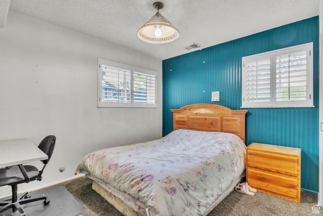 Carpeted bedroom featuring a textured ceiling and a desk | Image 13
