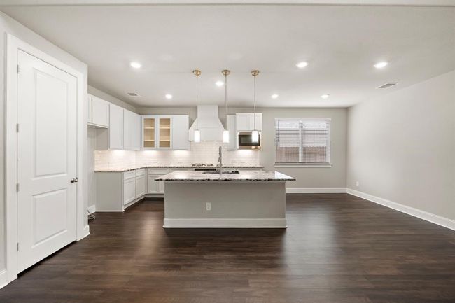 Gourmet kitchen features upgraded granite countertops, under cabinet lighting, a kitchen island overlookin the living room, and a breakfast bar for extra seating. | Image 8
