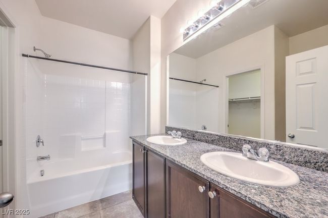 Full bath featuring double vanity, tile patterned flooring, a sink, and washtub / shower combination | Image 23