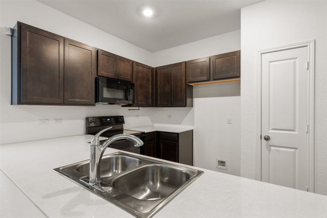 Kitchen with black appliances, dark brown cabinetry, and light countertops | Image 18