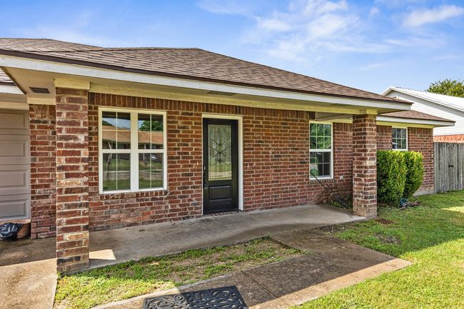 View of exterior entry with roof with shingles and brick siding | Image 8