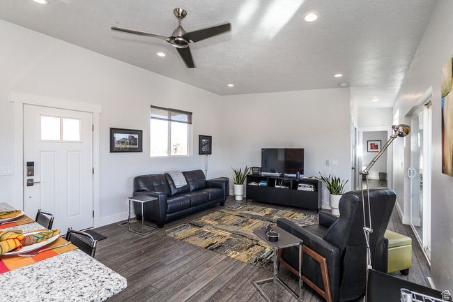 Living room with recessed lighting, dark wood-style flooring, baseboards, a textured ceiling, and ceiling fan | Image 39