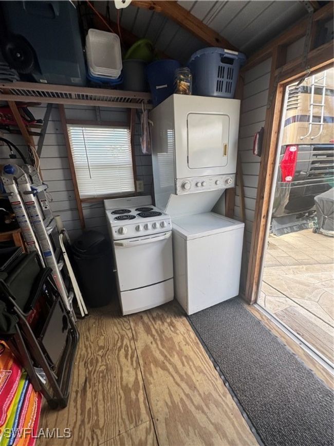 Clothes washing area featuring stacked washing maching and dryer, wood-type flooring, and wood walls | Image 30
