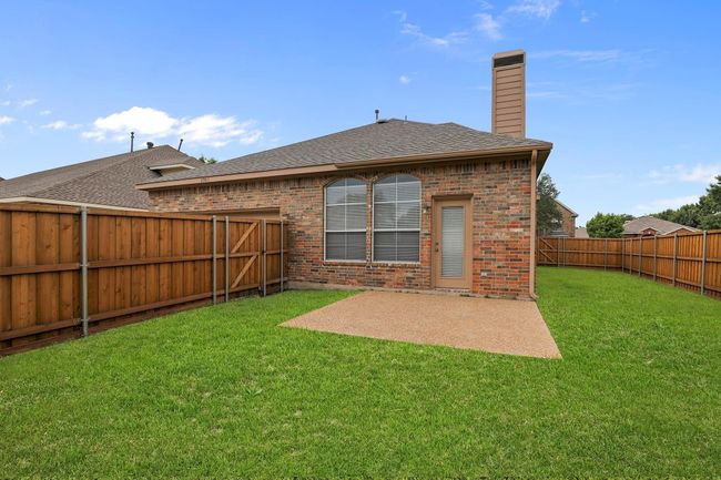 Back of property featuring brick siding, a chimney, a fenced backyard, a shingled roof, and a patio area | Image 14