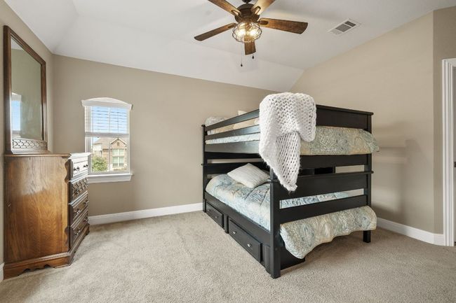 Bedroom 4 upstairs with carpet flooring, baseboards, vaulted ceiling, a ceiling fan, and walk in closet | Image 36